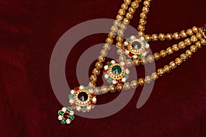 Multi layered artificial golden rani haar jewelry on a red background