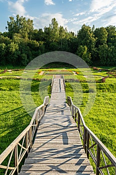 Multi-level wooden gangway in a picturesque place with a field and a forest. Summer evening before sundown. Nature landscape
