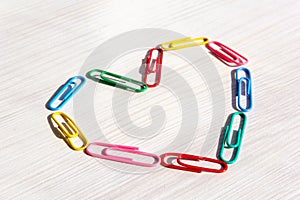 Multi olored paper clips. Paper clip heart on a light table. Heart close up. Romantic concept. Office and documents concept.