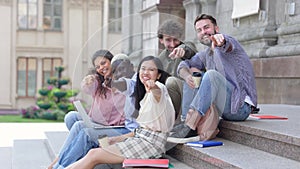 multi-racial group of students sitting on the steps of the campus.