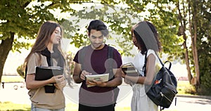 Multi racial students discussing subject standing at park