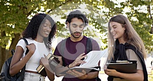 Multi racial students discussing subject standing at park