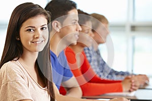 Multi racial teenage pupils in class, one smiling to camera