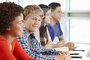 Multi racial teenage pupils in class, one smiling to camera