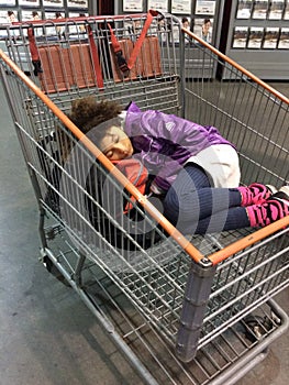 Multi Racial tween girl asleep in shopping cart