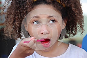 Multi Racial tween girl close up eating red ices