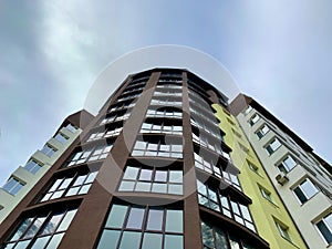 Multi-storey building on a background of blue sky. Tall building with mirrored windows, bottom view