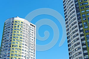 Multi-storey building in the form of a cylinder and painted in white and green colors against a blue sky.