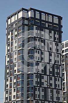 A multi-storey gray building standing against a blue sky. Modern high-rise residential buildings in the city. Beautiful decoration