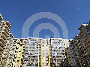 A multi-storey house against a blue sky. A new modern apartment building with glass balconies. Residential area. Realty. Copy