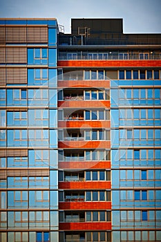 Multi-storey residential building with orange balconies against a blue sky