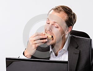 Multi tasking businessman eats and works photo