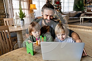 Multi-tasking freelance and fatherhood concept. Working single father with kids and laptop computer