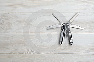 Multi tool with black handles on a white wooden background. Top view of desktop