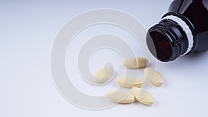 multi vitamins supplement spilled from bottle, on white background