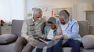 Multiage family members watching photoalbum, strong family bounds, togetherness