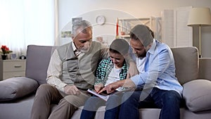 Multiage family members watching photoalbum, strong family bounds, togetherness