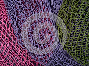 The multicolor background of the zero waste string bags, closeup of the knitted net. Selective focus