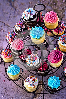 Multicolor frosting and sprinkles on cupcakes on three tier stand