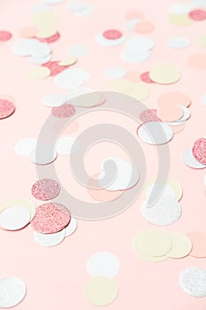 Multicolor pink, gold and white confetti on the light peach pink background, holiday celebration backdrop