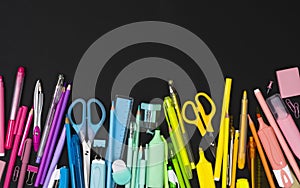 Multicolor stationery set, top view on black background with space