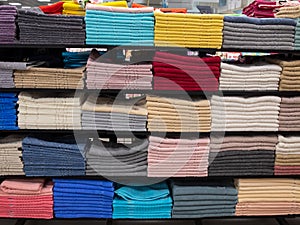 Multicolor towels on shelf in market, sale cotton towels, stack colored cotton towels