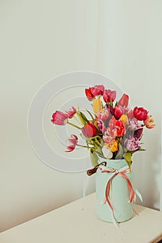 Multicolor tulips in metal vase on white background