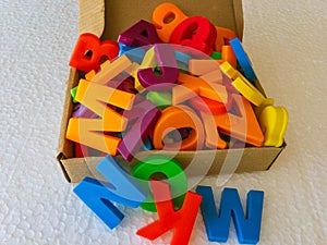 Multicolored alphabet letters in a box with white texture background