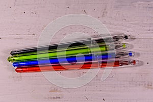 Multicolored ball pens on a wooden table. Top view