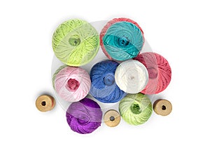 Multicolored balls and bobbins of woolen yarn, wooden thread sleeves on white isolated background. Needlework, handmade