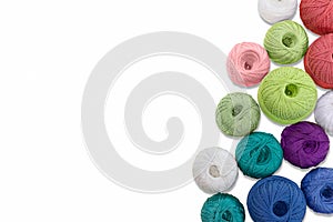 Multicolored balls and bobbins of woolen yarn, wooden thread sleeves on white isolated background. Needlework, handmade