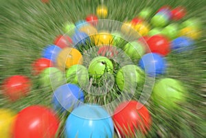 Multicolored balls - children's toys, on green grass, with radial blur