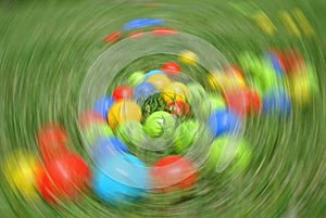 Multicolored balls - children's toys, on green grass, with radial blur