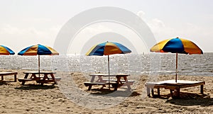 Multicolored Beach Umbrellas in wooden stand on beach.
