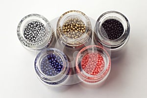 Multicolored beads in glass jars. Beads are poured on a white background. Plastic multi-colored polymers. Plastic pillets