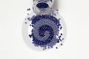 Multicolored beads in glass jars. Beads are poured on a white background. Plastic multi-colored polymers. Plastic pillets