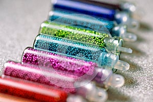 Multicolored beads for nail design close-up on a light gray background