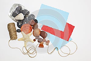 Multicolored blank sheets of paper for notes. Sea pebbles and shells crumbled from the glass. Twine for packing. Summer memories.