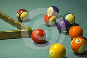 A multicolored blurred billiard balls with numbers are on the table with blue cloth and wooden pyromid