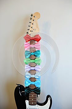Multicolored bow ties on a guitar fretboard neck. White background, free space for text