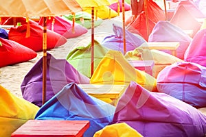 Multicolored bright beach umbrellas, ottomans and tables in the beach cafe. Summer multicolored background.