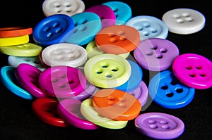 Multicolored buttons lie on a black background