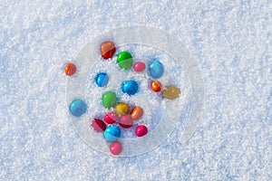 Multicolored candies, dragee in the snow. Sweets in the snow. Valentine's Day. Sweets as a gift. Romantic background for