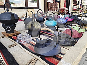 multicolored cast iron teapots on display at the market for sale.