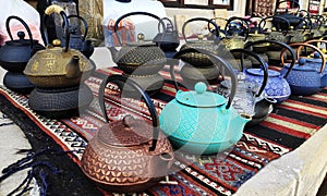 multicolored cast iron teapots on display at the market for sale.