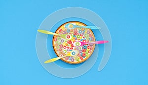 Multicolored cereals and spoons in a bowl with milk, top view on a blue background