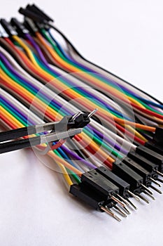 Multicolored computer wires and tweezers on a white background
