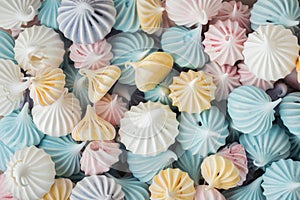 Multicolored crispy meringue cookies as a textured background. Close up of twisted meringue. Pastel colors. Background for