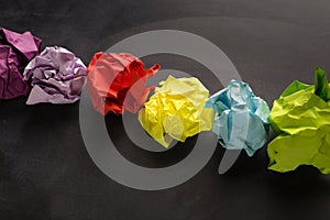 Multicolored crumpled paper balls over black background