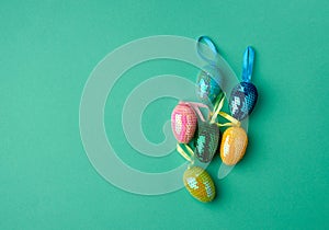 Multicolored decorative Easter eggs decorated with sequins on a green background
